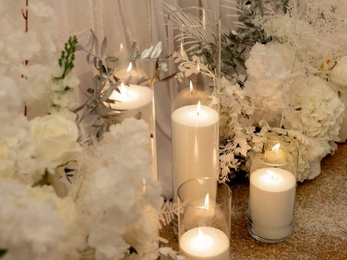Weiße Kerzen, florale Details und ruhige Lichtstimmung für Premium Eventdesign.