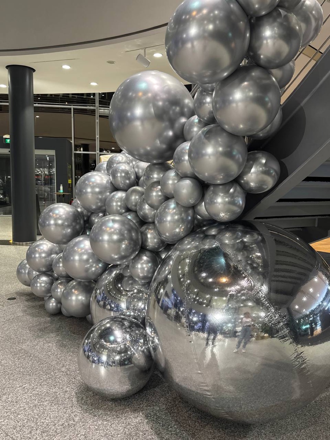 Corporate Event mit silberner Balloninstallation.