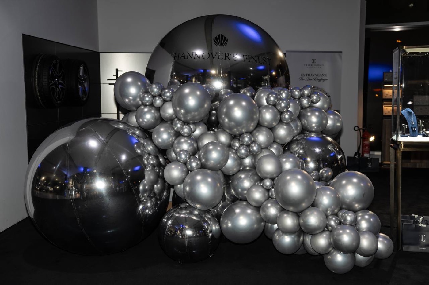 Silberne Balloninstallation mit dunkler Eventwand.