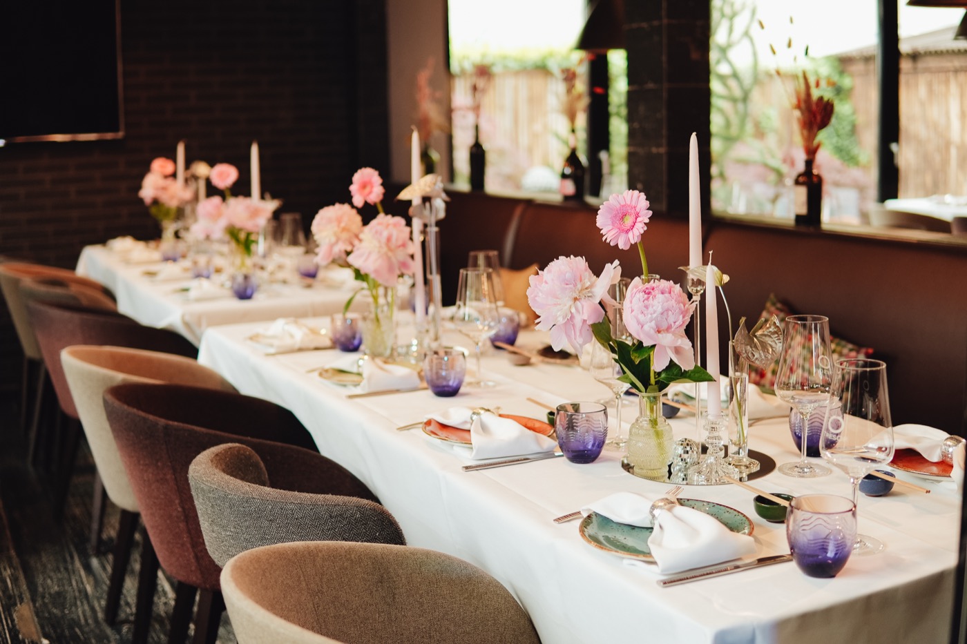 Elegante Hochzeitstafel mit rosa Blumen, Kerzen und gedeckten Plätzen.