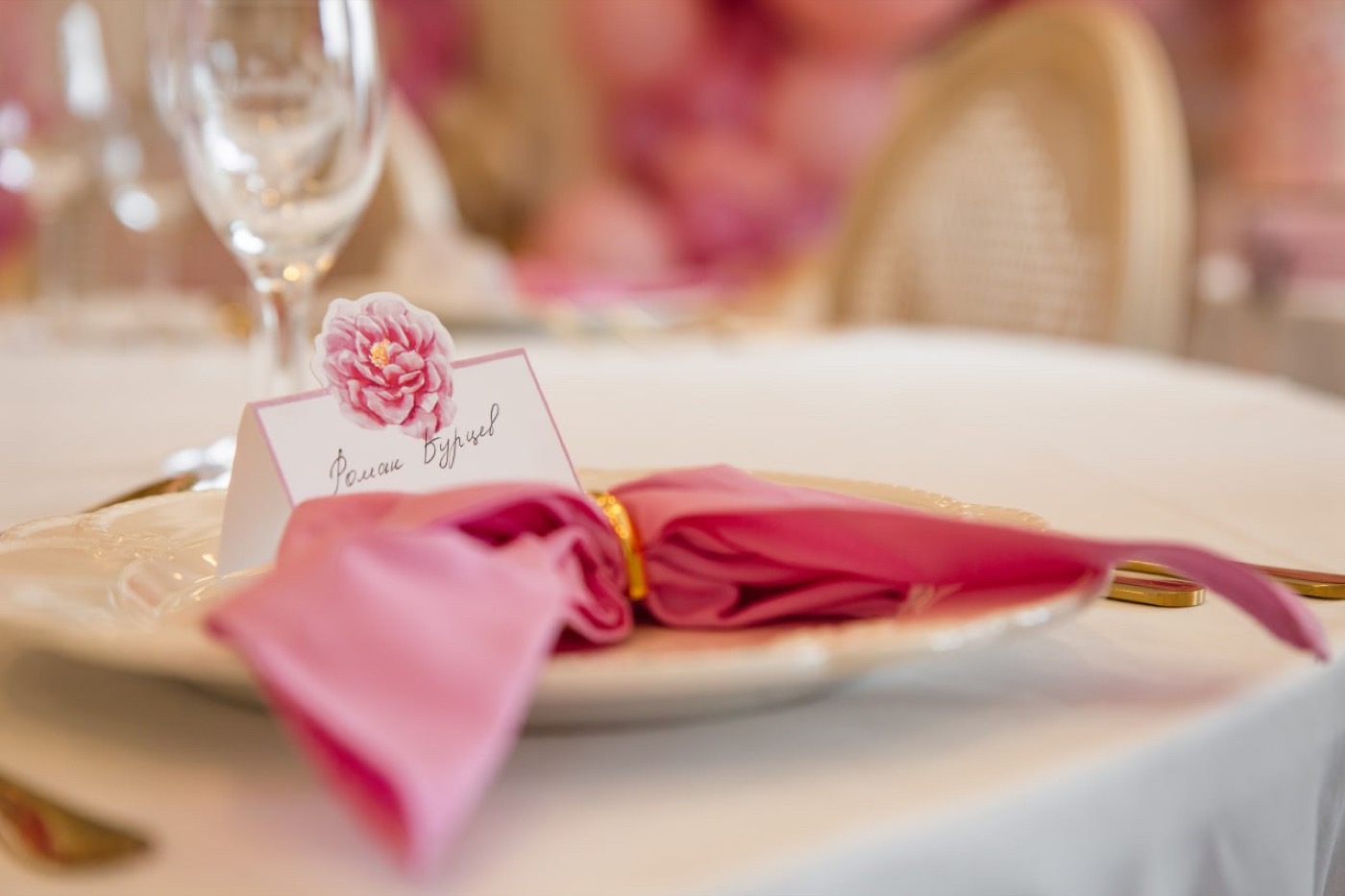 Tischdetail mit rosa Serviette, goldenem Besteck und abgestimmter Floristik.