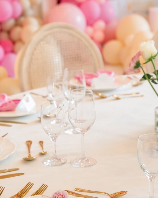 Rosa Tischdekoration mit goldenen Bestecken, Serviette und floralen Details.